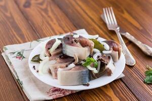 lightly salted mackerel with onions and spices on a wooden table photo