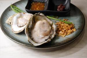 Fresh oysters with dipping sauce on the dining table photo