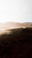 Clear river with rocks leads towards mountains lit by sunset video