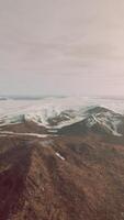 large snow patch left over on the volcanic rock field of a mountain in summer video
