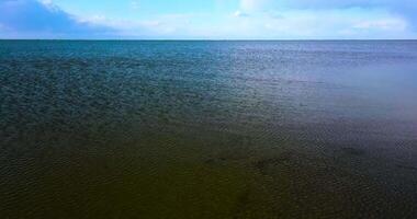 Back motion from rippling sea to sandbank under bright sky video