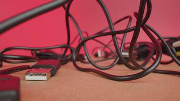 Tangled wires of USB cables lie on table on pink background video