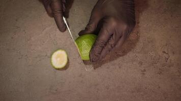 Person cuts lime into slices using sharp knife macro video
