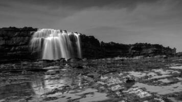 Big waves create beautiful sea views of waterfalls and water flows in Karang Taraje, Sawarna Beach, Indonesia. A favorite location for domestic and foreign photographers to hunt for photos and videos.