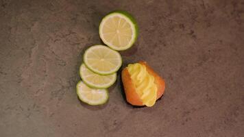 Ruddy cupcake with custard and lime lie on brown table video