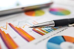 Pen resting on paper with colorful bar and pie charts representing business results photo