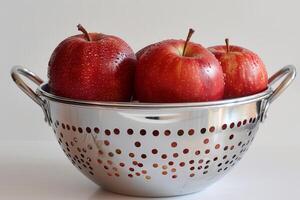 Red apples with water droplets resting in colander photo