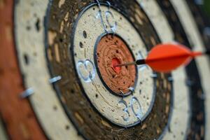 Red arrow hitting the center of an old target on a sunny day photo
