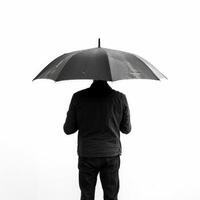 Man holding umbrella standing backwards on white background photo