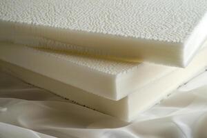 Stack of memory foam mattress toppers resting on white fabric photo