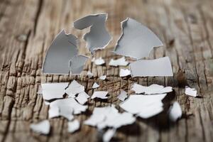 Eggshell breaking on rustic wood table depicting fragility photo