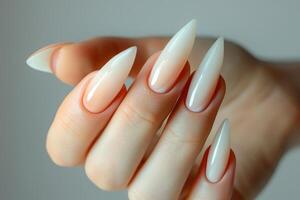 Woman showing long almond shaped ombre nails manicure on gray background photo