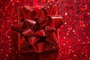 Shiny red gift box with sparkling bow on red glitter background photo