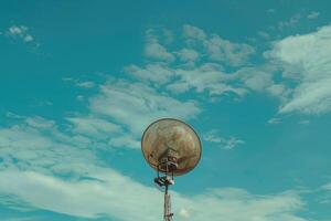 Old rusty loudspeaker pointing up to the blue sky on cloudy day photo
