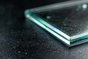 Closeup of a thick piece of glass resting on a black surface photo