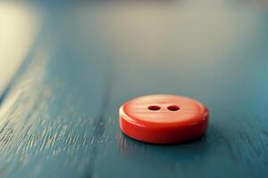 Single red button lying on a blue wooden surface photo