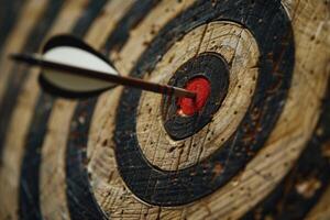 Arrow hitting the center of an old target on wooden background photo