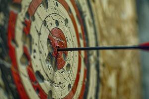 Arrow hitting the center of an old target on wood background photo