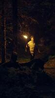 A man is holding a torch as he wanders through a forest during the night time hours video