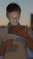 Joyful and youthful individuals are engaged with a tablet while enjoying a beautiful sunset video