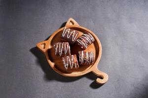 Chocolate roll cake with fresh cream in wooden plate isolated on dark background. chocolate swiss roll cake. top view. photo