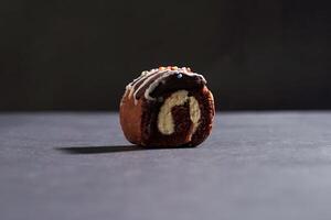 Chocolate roll cake with fresh cream isolated on dark background. chocolate swiss roll cake. photo