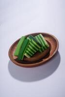 Sticky layer cake or Kue Lapis on wooden plate isolated on white background. Indonesian traditional dessert made from rice flour and coconut milk, steamed layer by layer served on banana leaves. photo