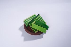 Sticky layer cake or Kue Lapis on wooden plate isolated on white background. Indonesian traditional dessert made from rice flour and coconut milk, steamed layer by layer served on banana leaves. photo