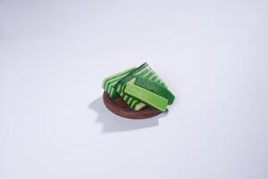 Sticky layer cake or Kue Lapis on wooden plate isolated on white background. Indonesian traditional dessert made from rice flour and coconut milk, steamed layer by layer served on banana leaves. photo