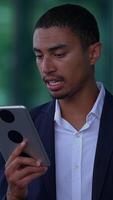 A businessman is deeply engaged with his tablet while situated in a modern office setting video
