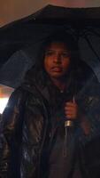 A person is thoughtfully holding an umbrella while navigating through rainy weather video