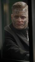An intriguing character with distinct, eyecatching tattoos captured in a dark, atmospheric setting video