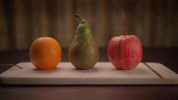 A Beautiful Arrangement of Fresh Fruits on a Wooden Board An Orange, a Pear, and an Apple video