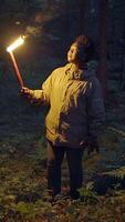 A person is holding a torch while navigating through a dark and mysterious forest area video