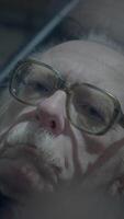 An introspective elderly man gazes thoughtfully at his reflection within the glass surface video