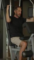 A man is actively engaging in a focused exercise routine at the gym using strength equipment video