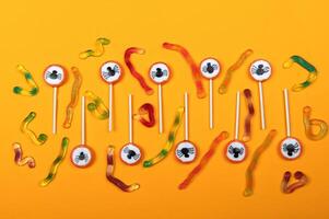 Halloween candy with black spiders and cobweb on orange color background,top view photo