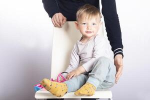 The mother's hands protect the baby boy, who is sitting on a chair photo