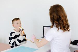 Boy testing breathing function by spirometry in doctors office. Diagnosis of respiratory function in pulmonary disease photo