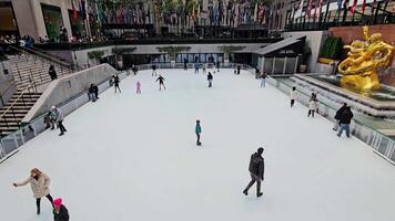 New York State, United States, 10 December 2024 Rockefeller Ice Rink in Action, Visitors and locals glide across the Rockefeller Center ice rink as lush greenery, international flags video