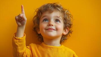 young boy with curly hair points upwards, smiling joyfully photo