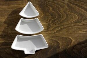 An empty Christmas or New Year wooden plate in the shape of a Christmas tree on a wooden background. View from above photo