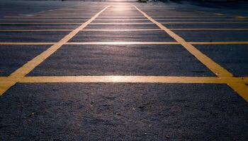 A low angle view of a parking lot with yellow lines, with the sun shining in the background. photo