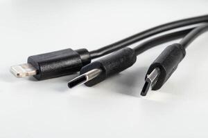 Universal black 3 in 1 charging cable with different charging connectors on a white background, close-up. Type-c, usb-c, micro-usb photo
