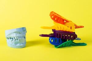 Blue plaster cast of a dental jaw and a dental tray for an impression of a dental jaw on a yellow background. The concept of orthodontics in dentistry, the manufacture of dentures and crowns. photo