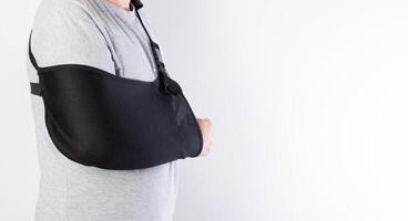 A man on a white background in a bandage to support his arm. Immobilization of the hand and forearm after injury. Rehabilitation after a broken bone. Orthopedics, copy space for text photo