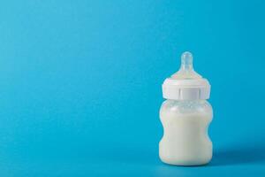 Baby bottle with milk for feeding babies on a blue background. Milk mixture enriched with bifidobacteria, vitamins and minerals. Copy space for text, healthy microbiota photo