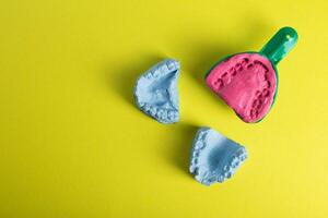 Dental spoon with alginate plastic mass for taking an impression of the dental jaw on a yellow background. Blue plaster dental jaw on a yellow background. Orthodontics in dentistry photo