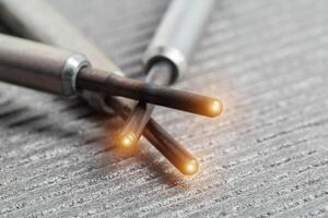 Serviceable modern ceramic glow plugs on a gray background. Orange glow, heating element. Pre-heating of a diesel engine, close-up photo