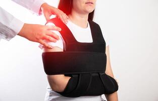 An orthopedic doctor examines a girl patient after a shoulder injury. Bandage on the shoulder joint after shoulder dislocation and bone fracture. Post-traumatic immobilization photo